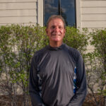 Image of Jerry Santoro in front of a building with bushes in the back.