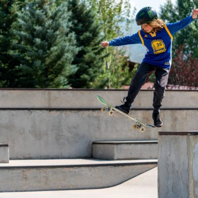 Child with helmet on riding a skateboard in a skatepark